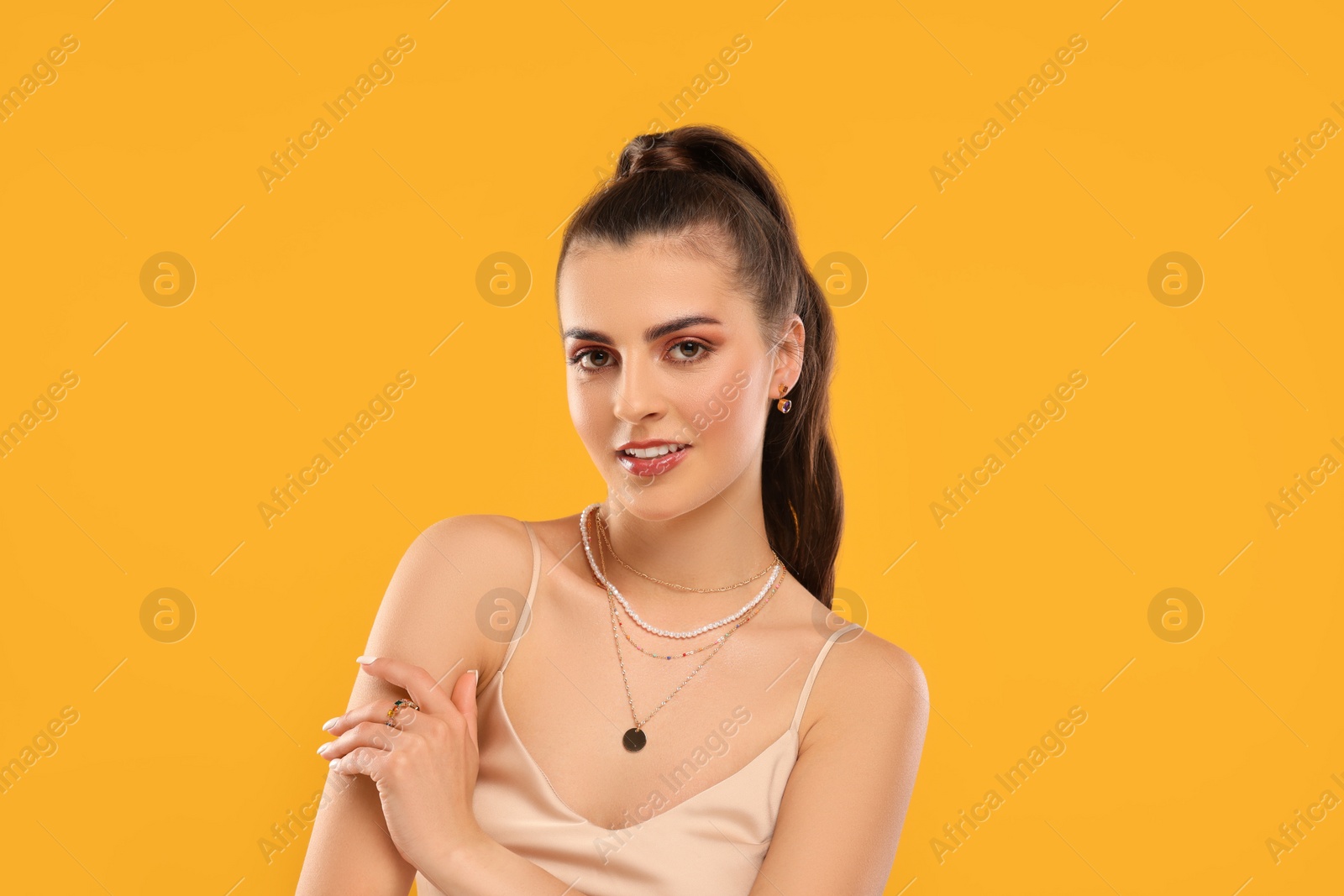 Photo of Beautiful woman with elegant jewelry on orange background