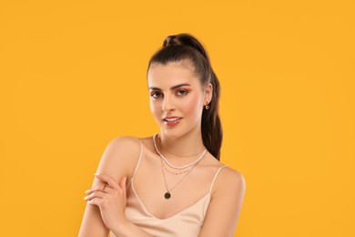 Beautiful woman with elegant jewelry on orange background