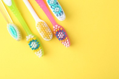 Photo of Different toothbrushes on yellow background, flat lay. Space for text