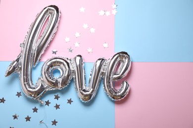 Photo of Foil balloon in shape of word LOVE on color background, above view