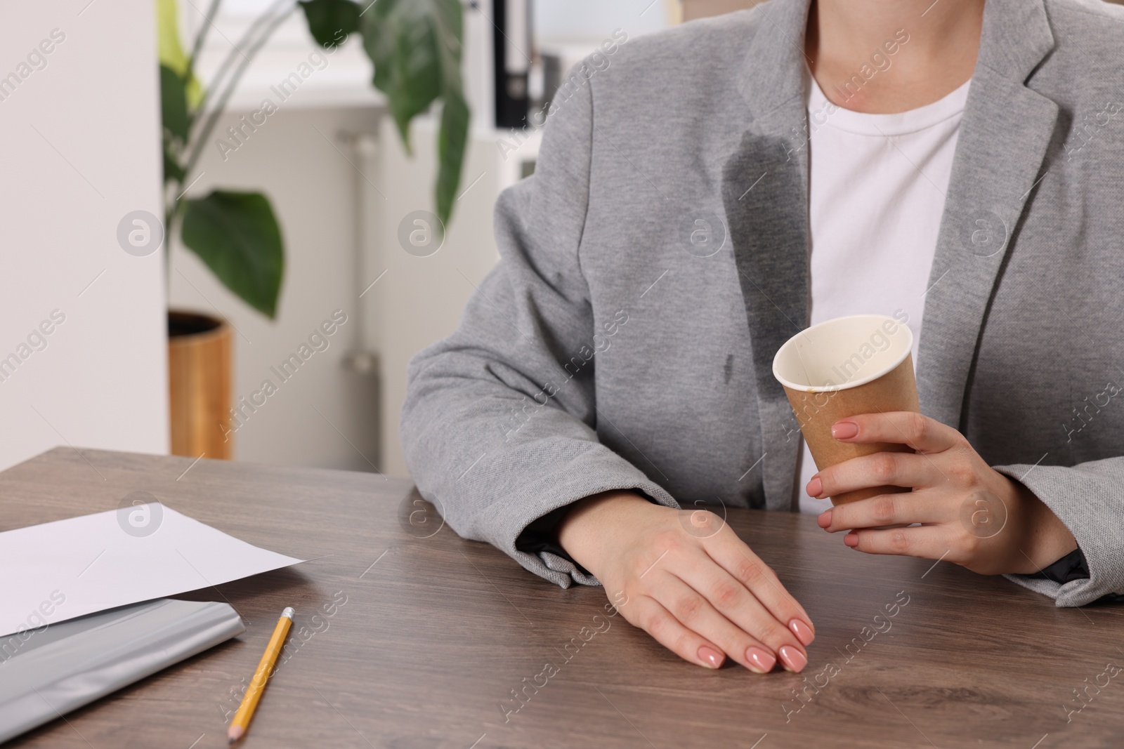 Photo of Woman showing stain from coffee on her jacket at wooden table indoors, closeup