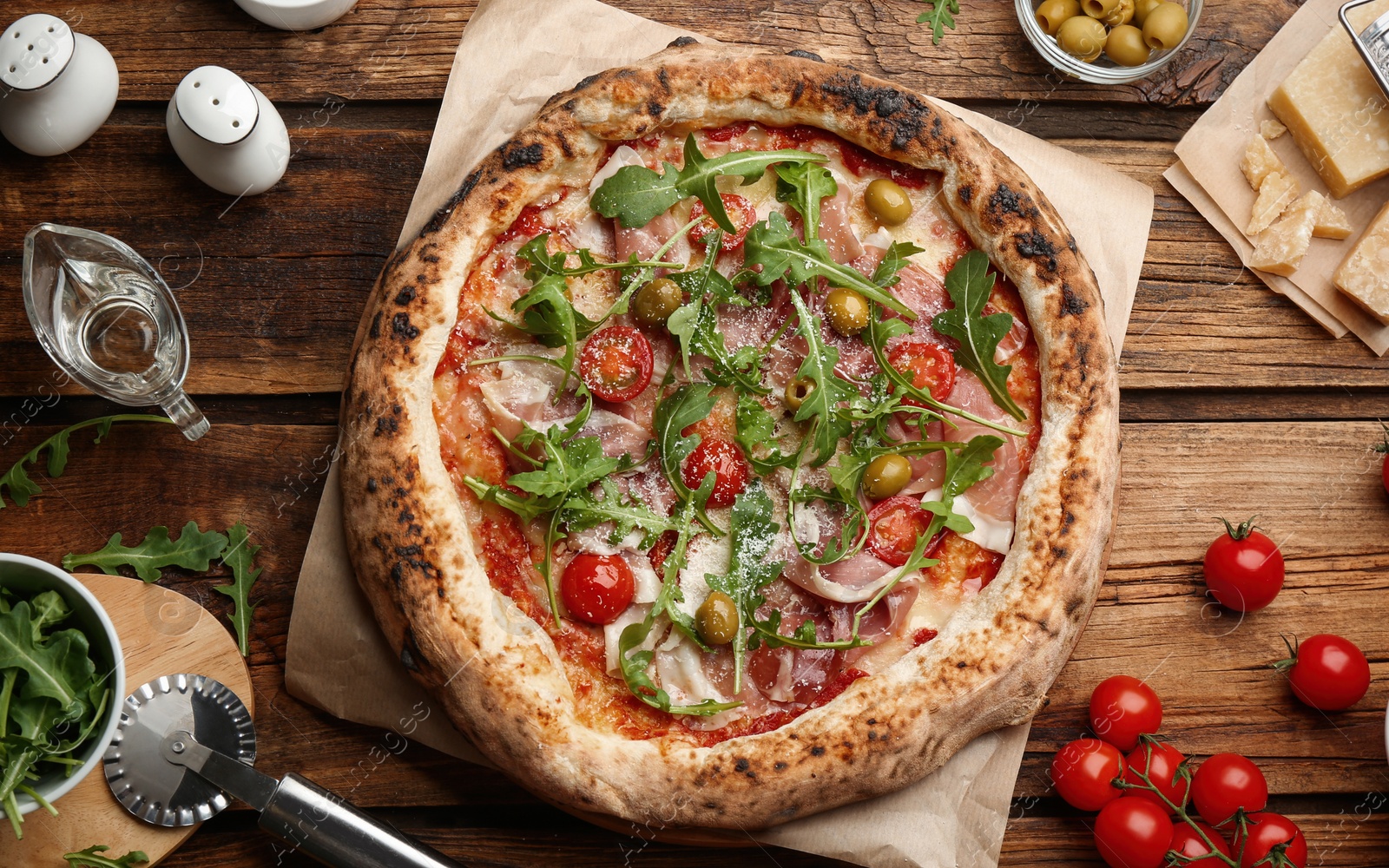 Photo of Tasty pizza with meat and arugula on wooden table, flat lay