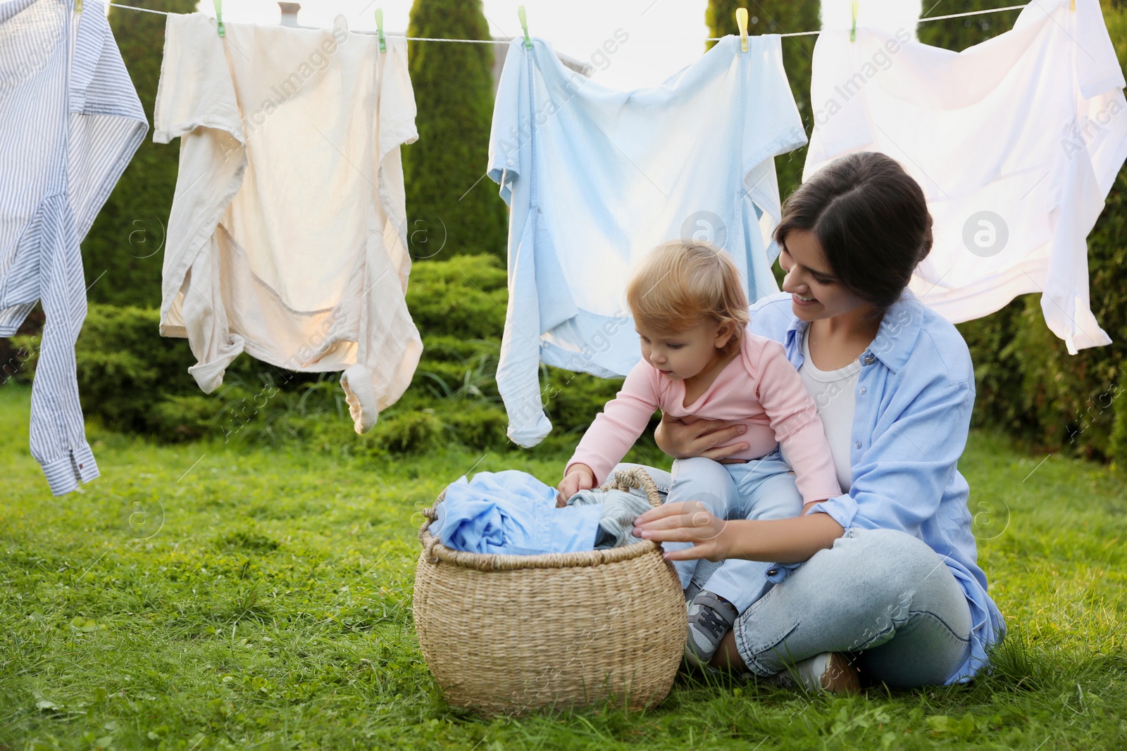 Photo of Mother and daughter near washing line with drying clothes in backyard