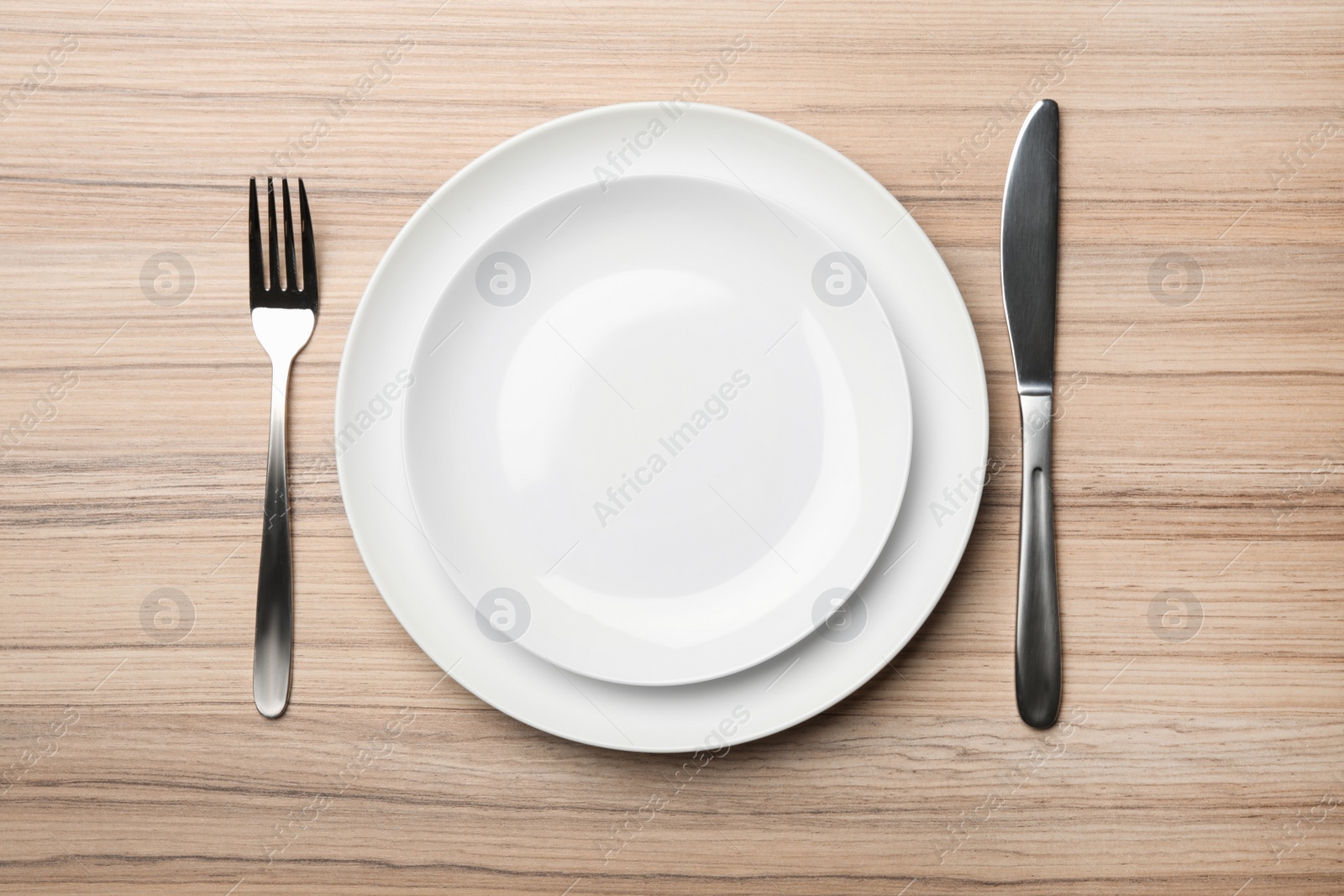 Photo of Stylish ceramic plates and cutlery on wooden background, flat lay