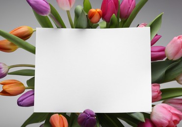 Photo of Blank birthday card on beautiful tulip flowers against grey background, flat lay. Space for text