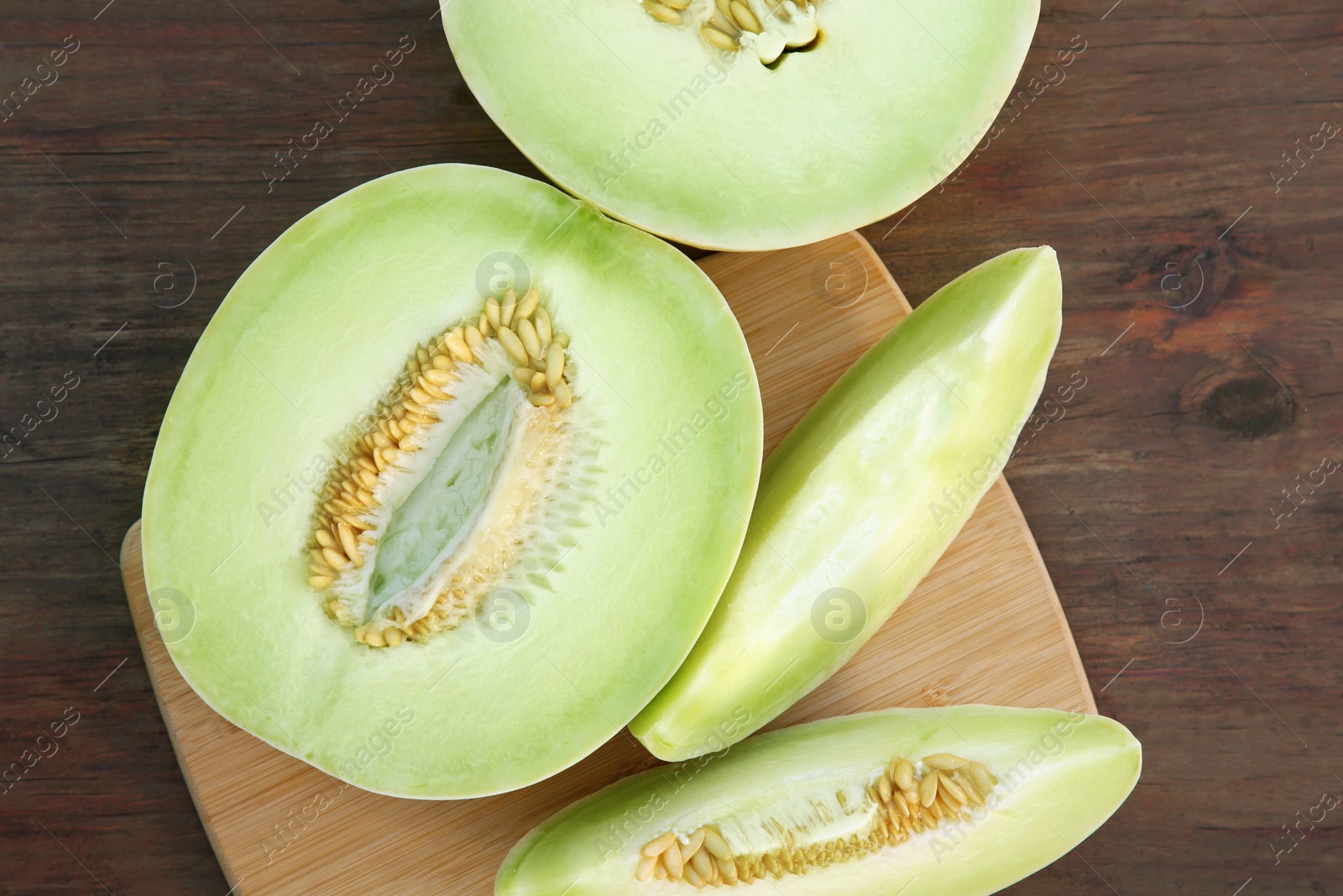 Photo of Cut tasty ripe melons on wooden table, flat lay