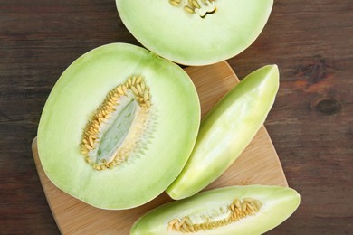 Cut tasty ripe melons on wooden table, flat lay