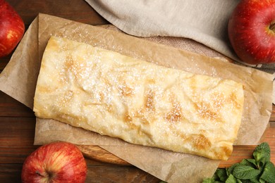 Photo of Delicious strudel, mint and fresh apples on wooden table, flat lay