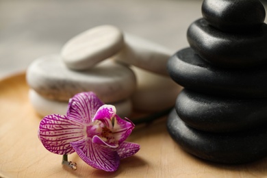 Photo of Spa stones and orchid flower on wooden plate, closeup