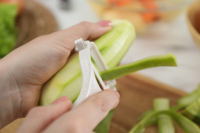 Woman peeling fresh zucchini at table, closeup