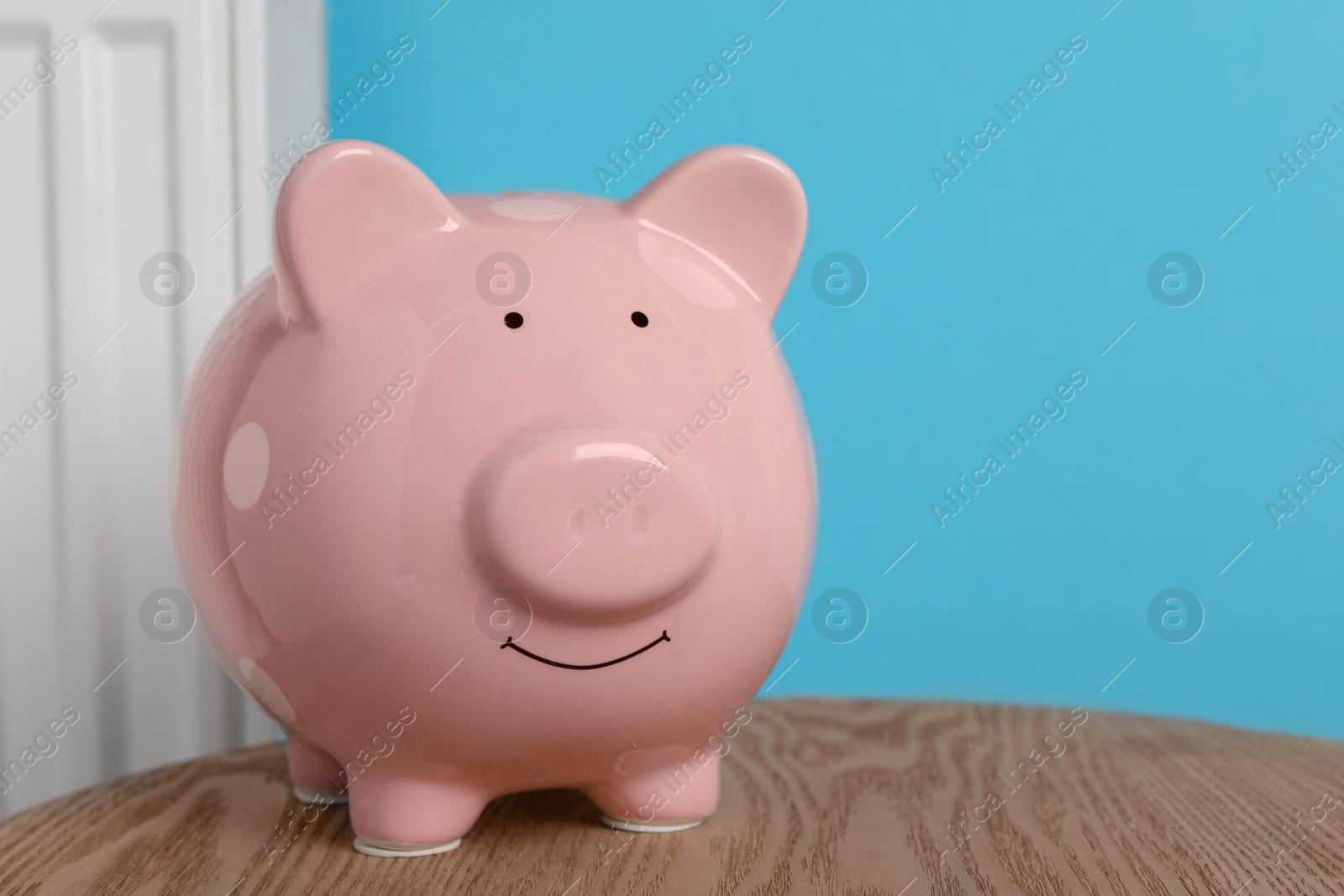 Photo of Piggy bank on wooden table near heating radiator, space for text