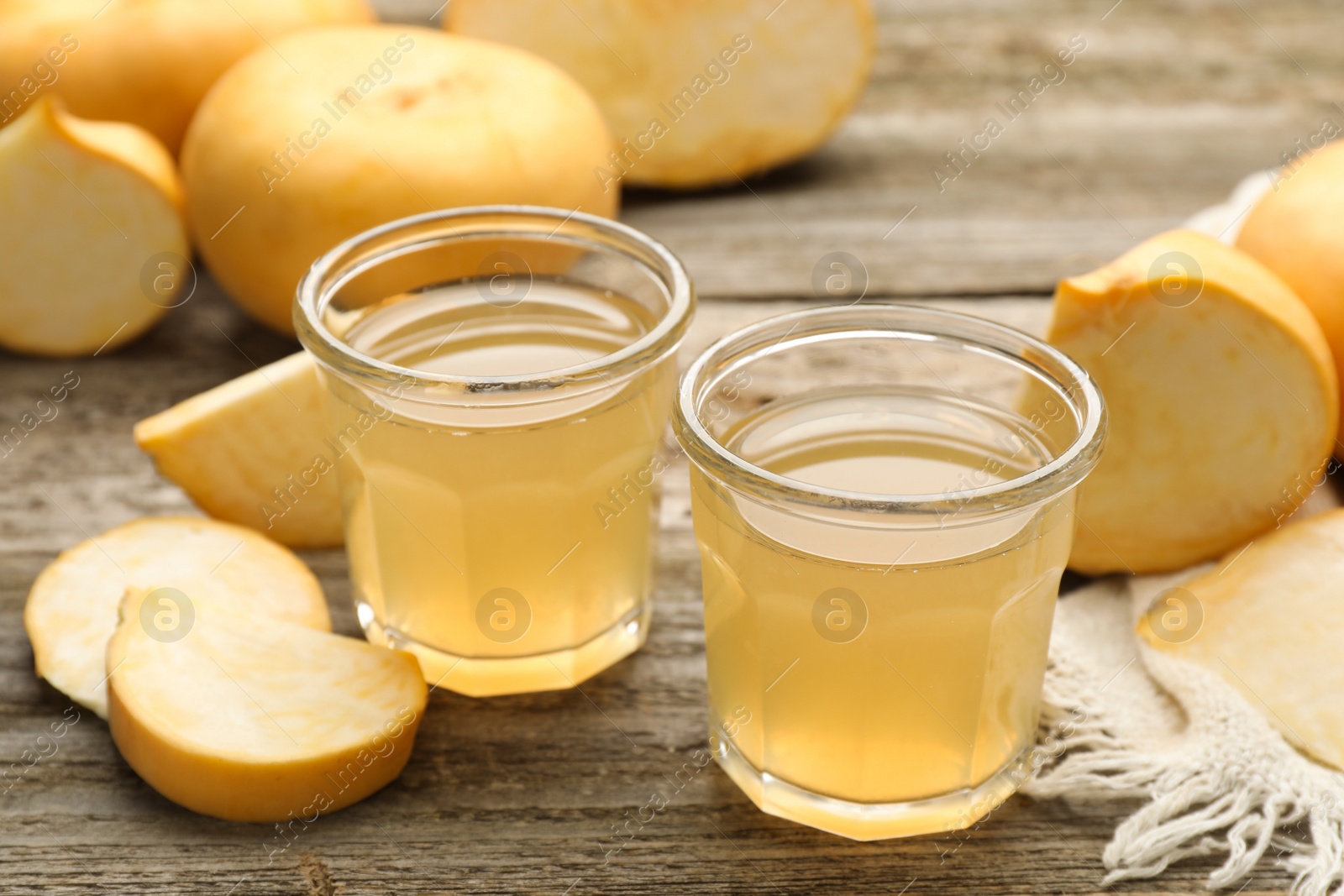 Photo of Glasses of freshly made turnip juice on wooden table