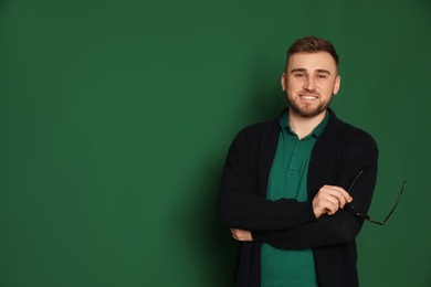 Portrait of young teacher with glasses on green background. Space for text