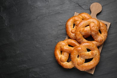 Photo of Delicious pretzels with sesame seeds on black table, top view. Space for text