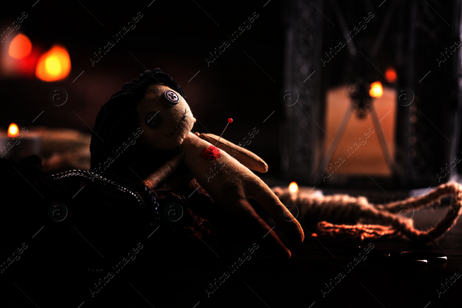Image of Female voodoo doll with pin in heart and ceremonial items on table