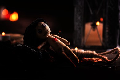 Female voodoo doll with pin in heart and ceremonial items on table