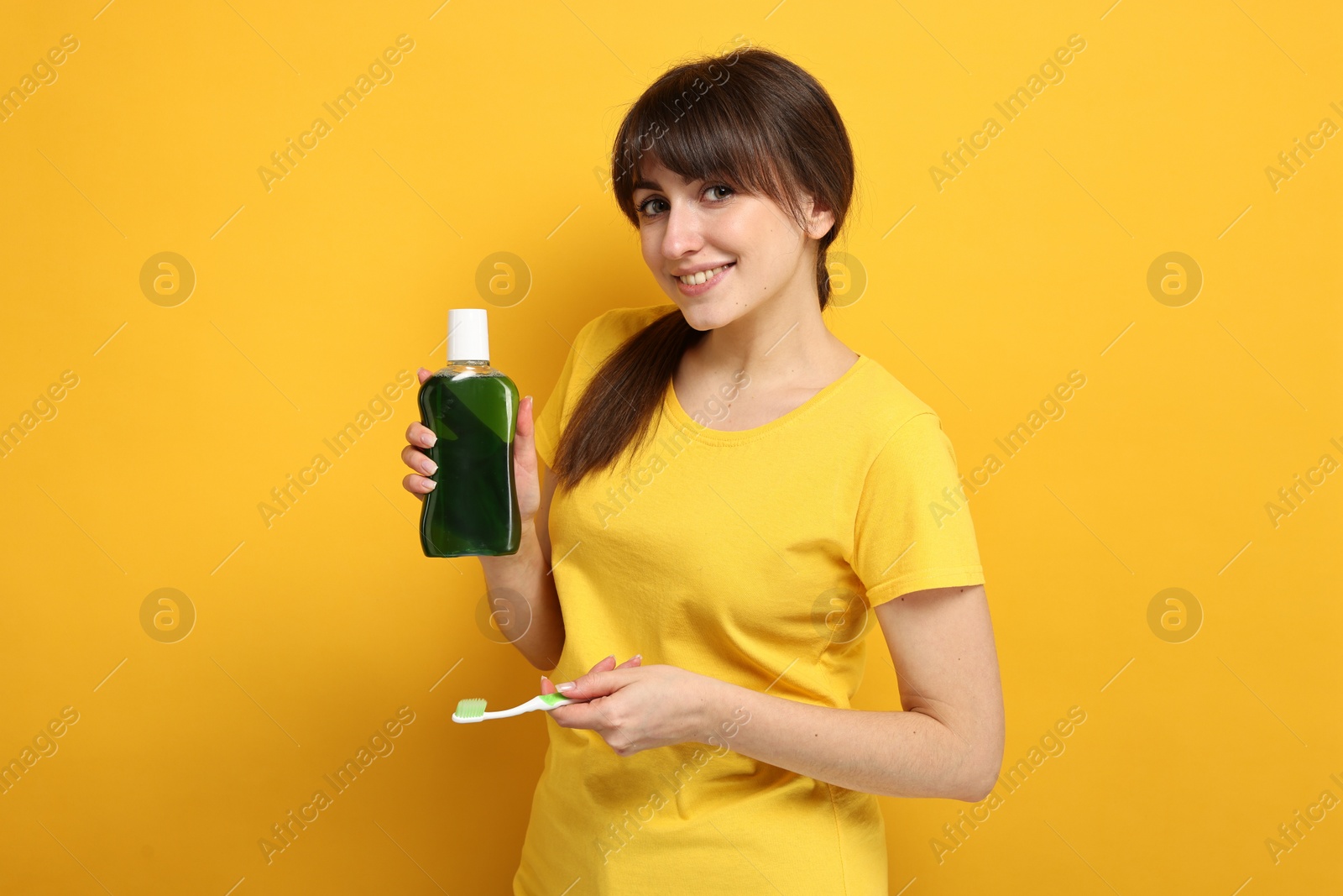 Photo of Young woman with mouthwash and toothbrush on yellow background