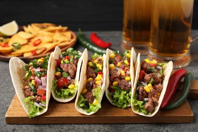 Photo of Delicious tacos with meat and vegetables on gray table, closeup