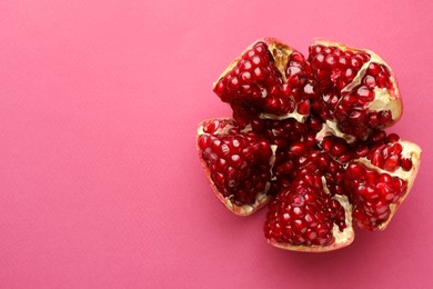 Photo of Cut fresh pomegranate on pink background, top view. Space for text