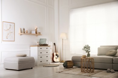 Living room with comfortable grey sofa and stylish interior elements near window