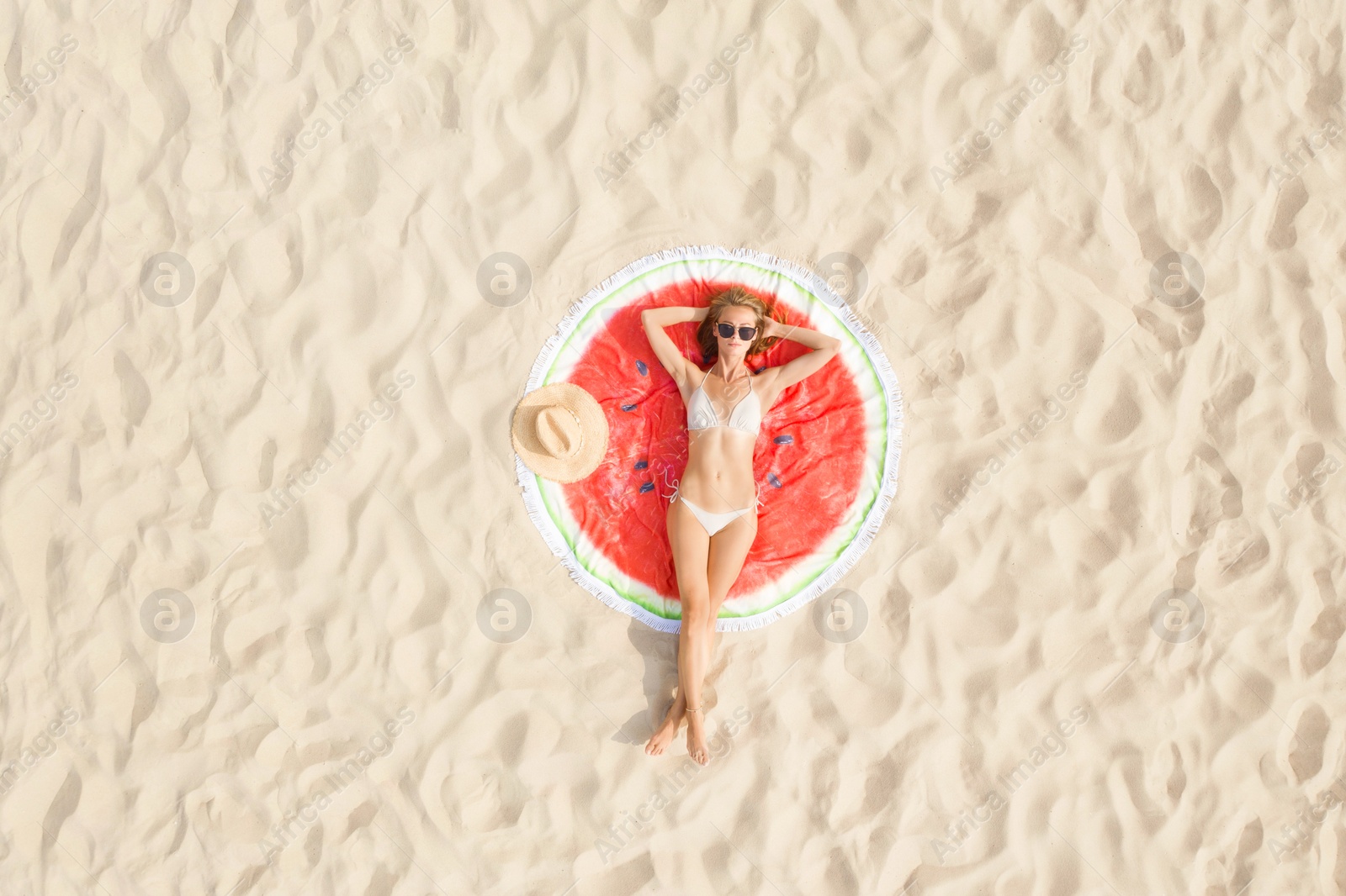 Image of Woman sunbathing on round beach towel at sandy coast, aerial view