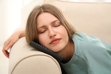 Photo of Lazy young woman sleeping on TV remote at home