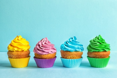 Photo of Delicious birthday cupcakes with cream on color background