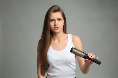 Young woman with hair loss problem on light background