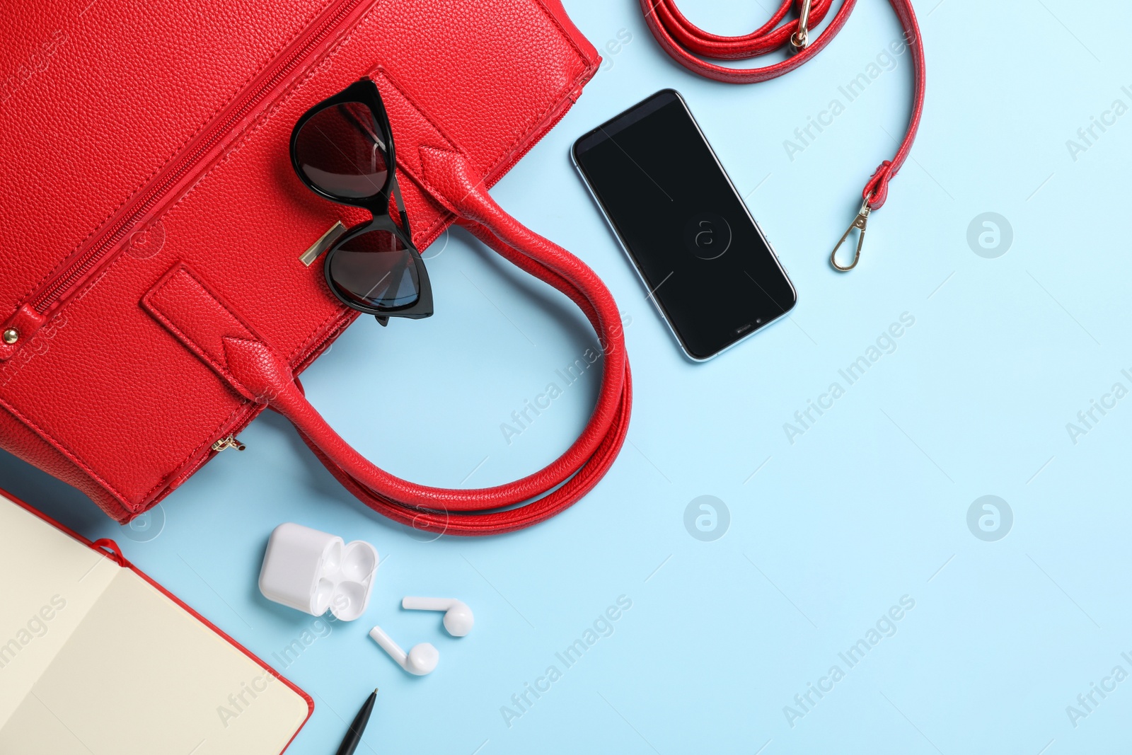 Photo of Stylish women's bag and different stuff on light blue background, flat lay. Space for text