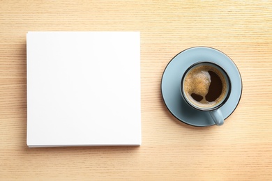 Photo of Blank paper sheets for brochure and cup of coffee on wooden background, flat lay. Mock up