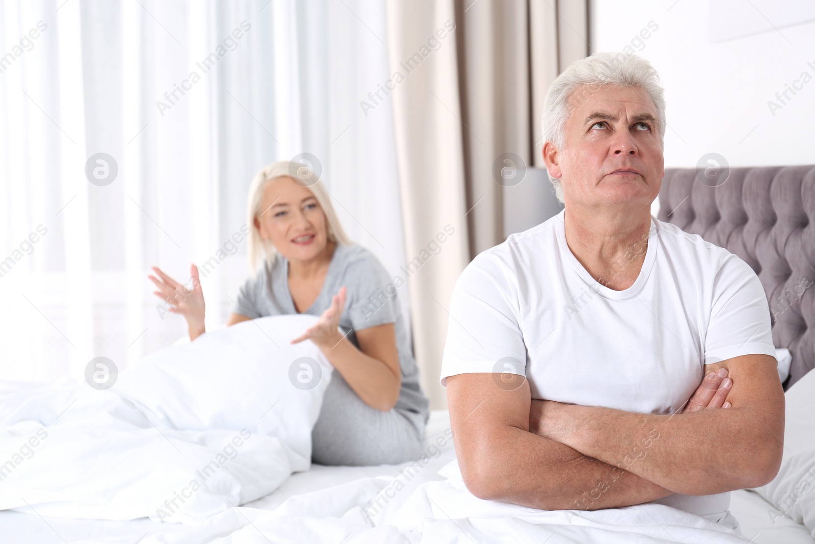 Photo of Mature couple having conflict in bedroom at home. Relationship problems