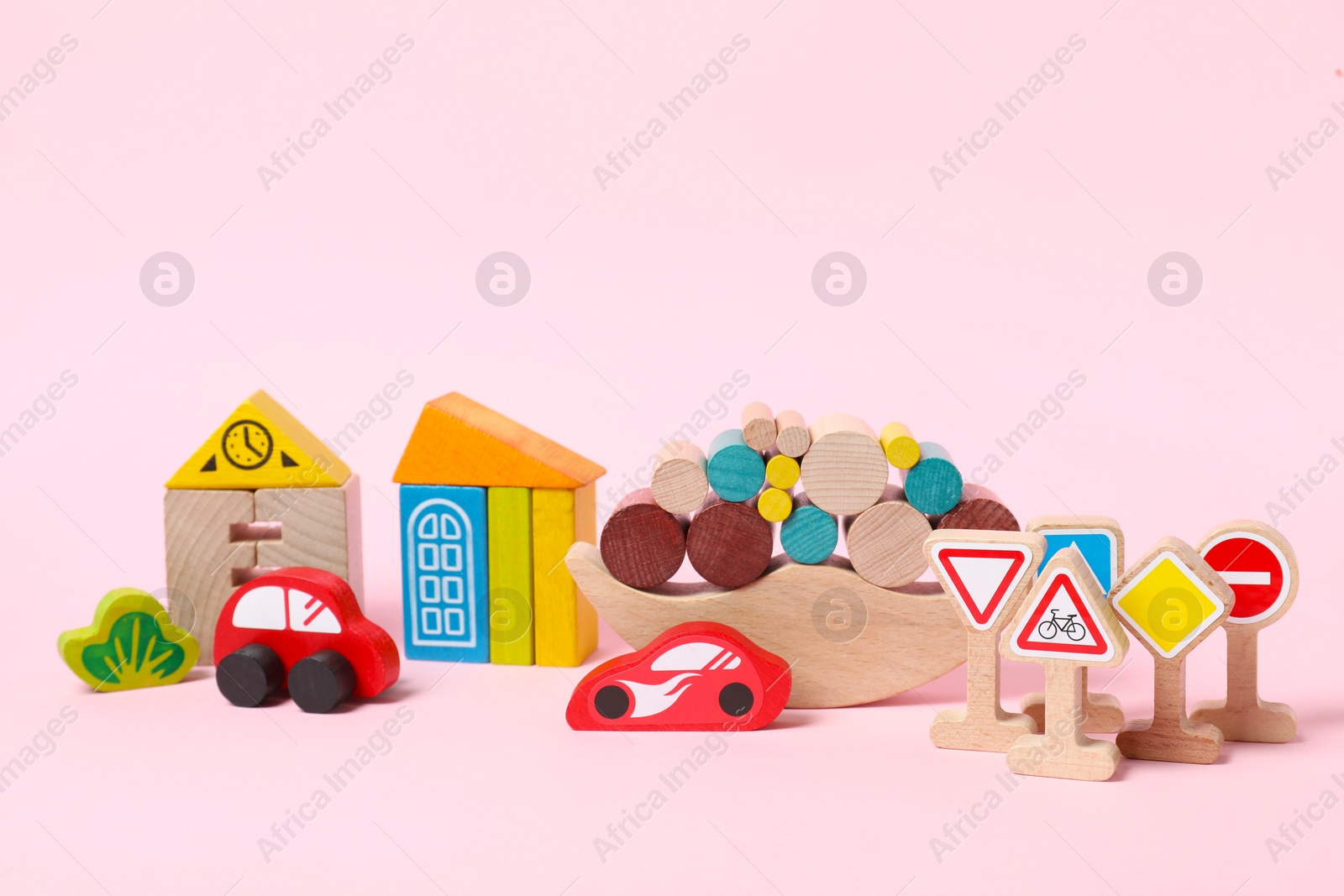 Photo of Different wooden toys on light pink background. Children's development