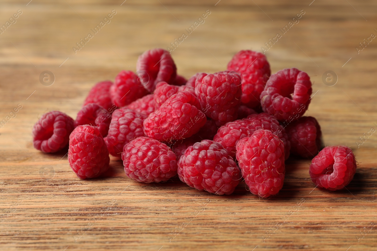 Photo of Heap of delicious ripe raspberries on wooden table, closeup