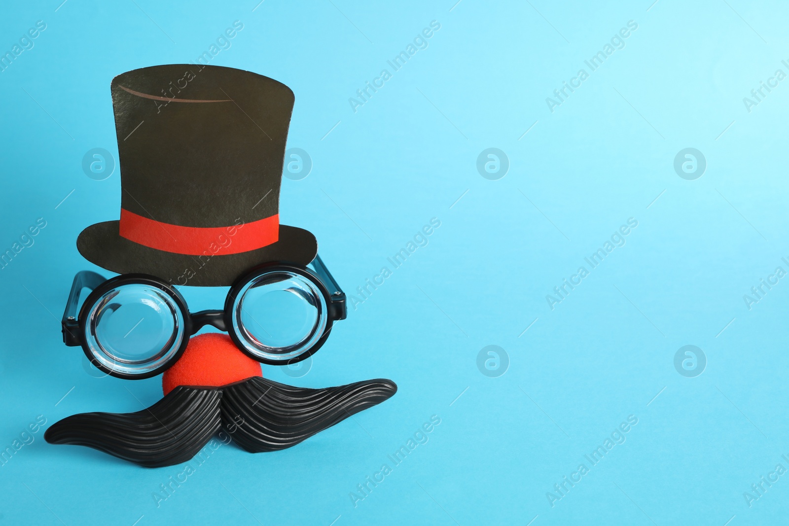 Photo of Funny face made with clown's accessories on light blue background, space for text