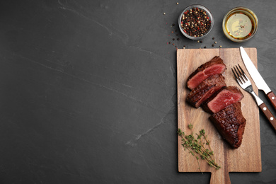 Photo of Delicious beef tenderloin served on black table. Space for text