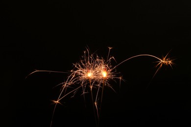 Photo of Burning sparklers glowing in dark, space for text