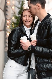 Photo of Lovely young couple with cups of coffee enjoying time together outdoors, closeup. Romantic date