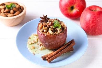 Photo of Tasty baked apple with nuts, honey, spices and mint on white wooden table