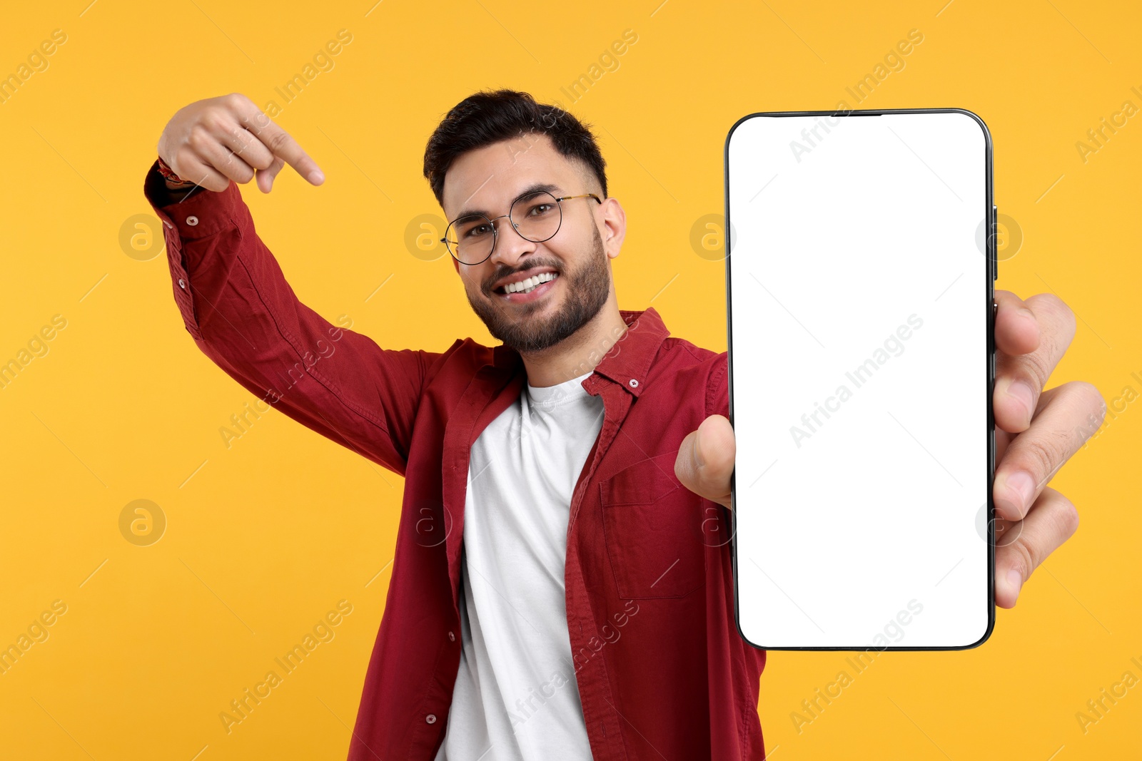 Image of Happy man holding smartphone with empty screen on orange background