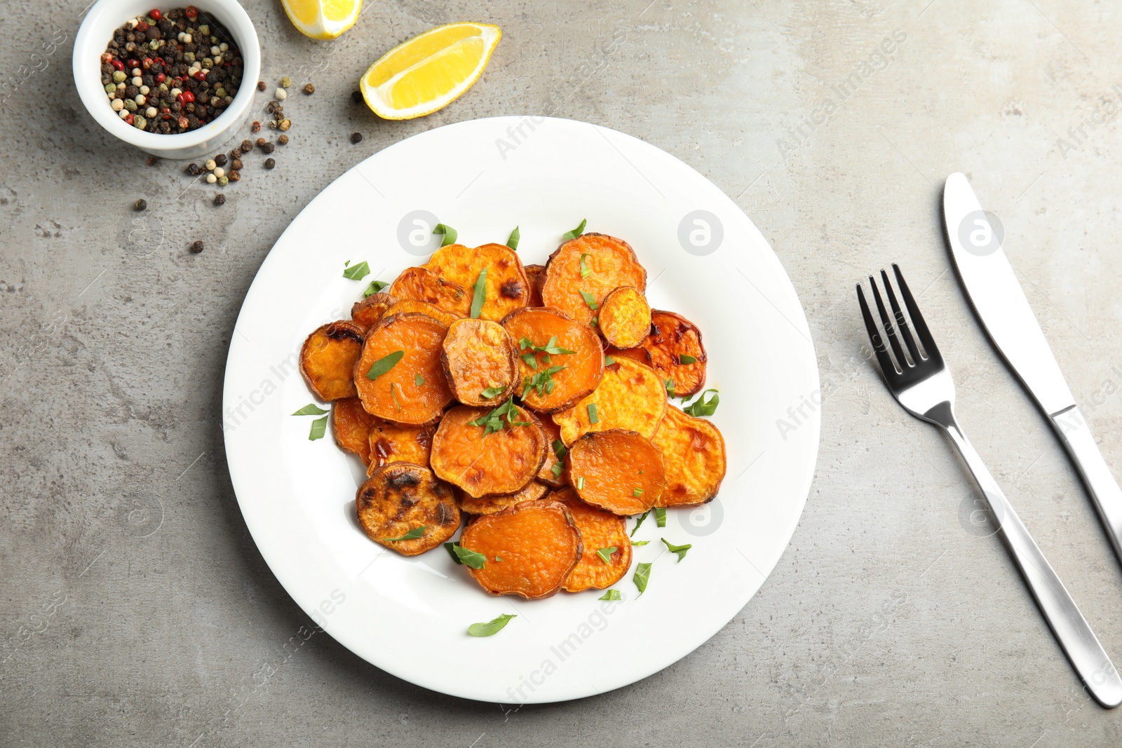 Photo of Plate with baked sweet potato slices served on grey table, top view