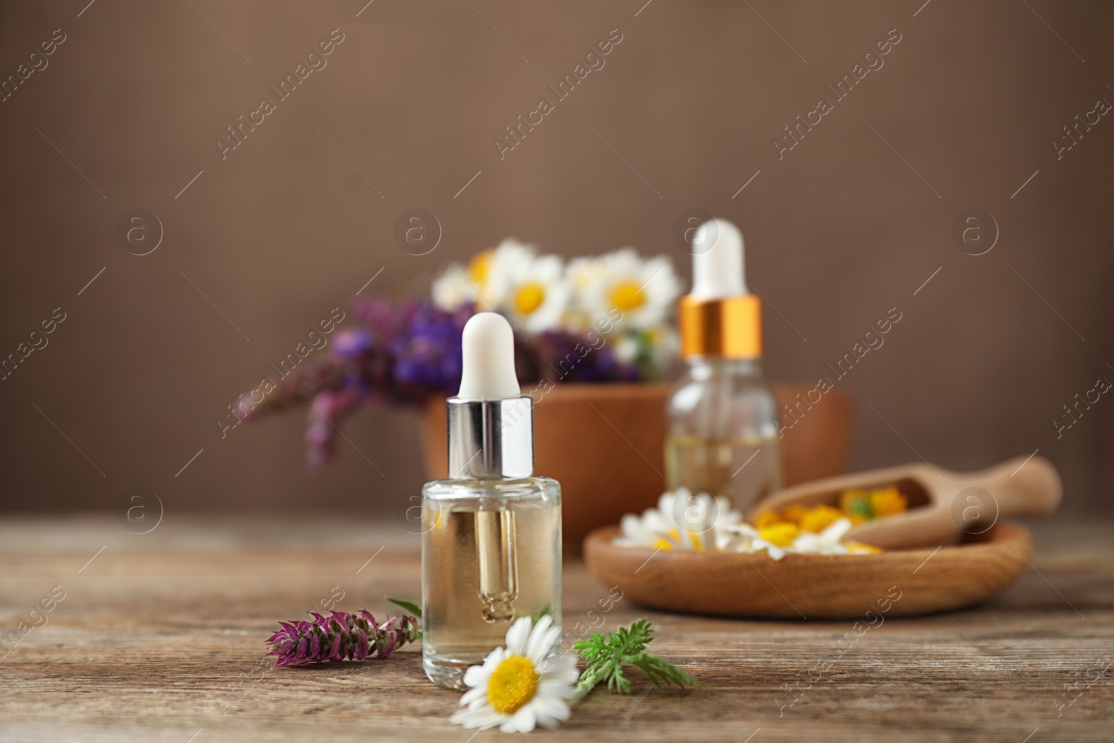 Photo of Bottles of essential oils and wildflowers on wooden table