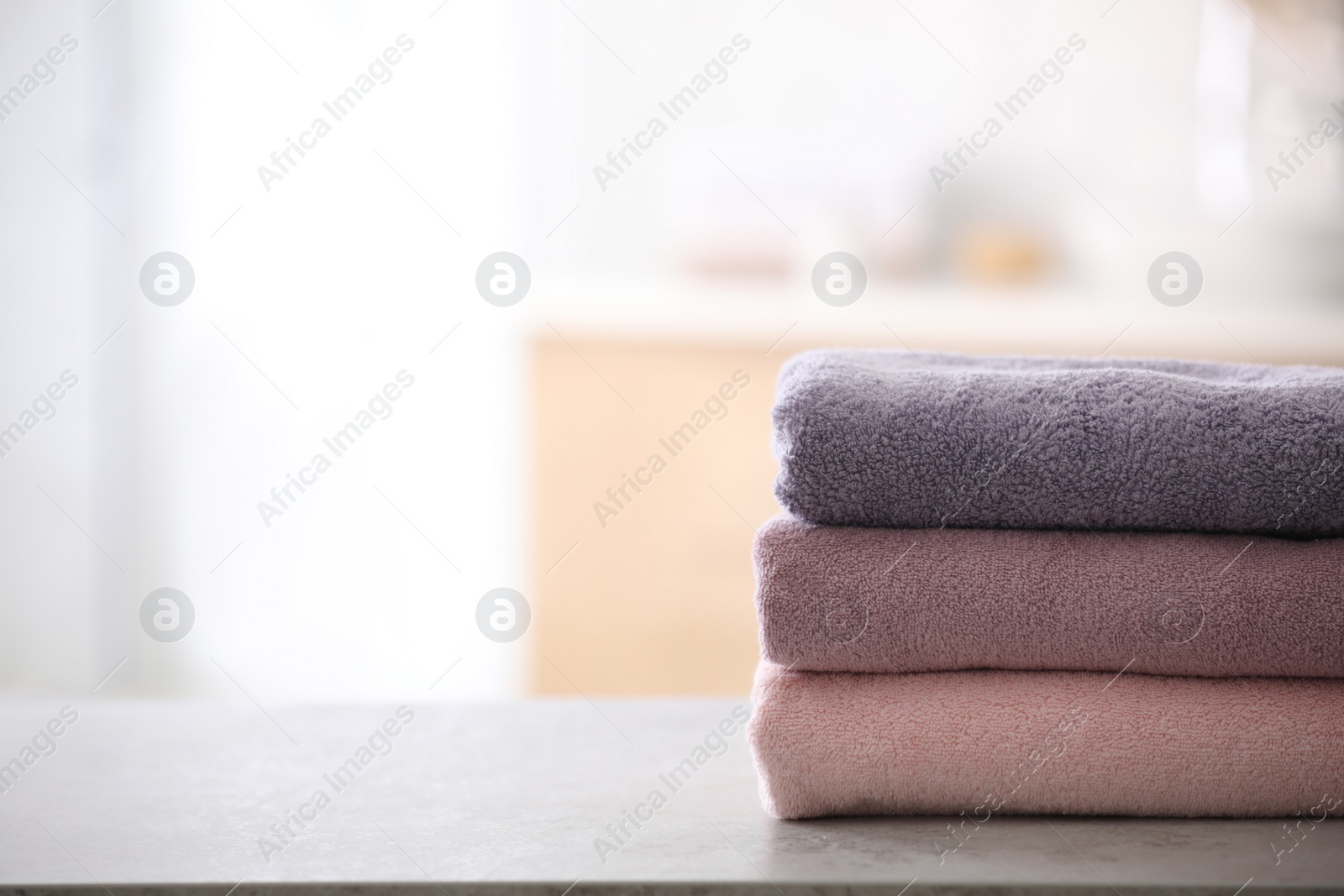 Photo of Stack of fresh towels on table in bathroom. Space for text