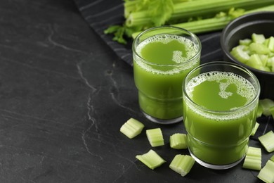 Photo of Glasses of delicious celery juice and vegetables on black table, closeup. Space for text