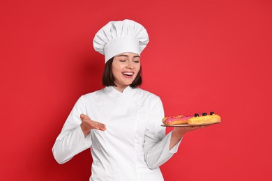 Happy confectioner with delicious eclairs on red background