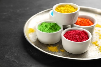 Photo of Colorful powder dyes on black background, closeup. Holi festival