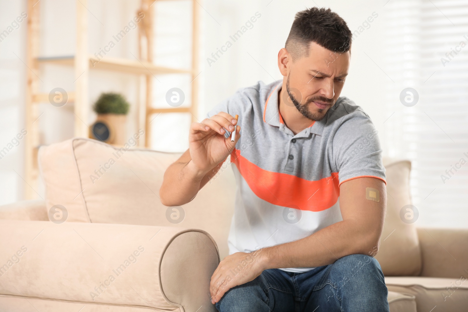 Photo of Emotional man with nicotine patch and cigarette at home