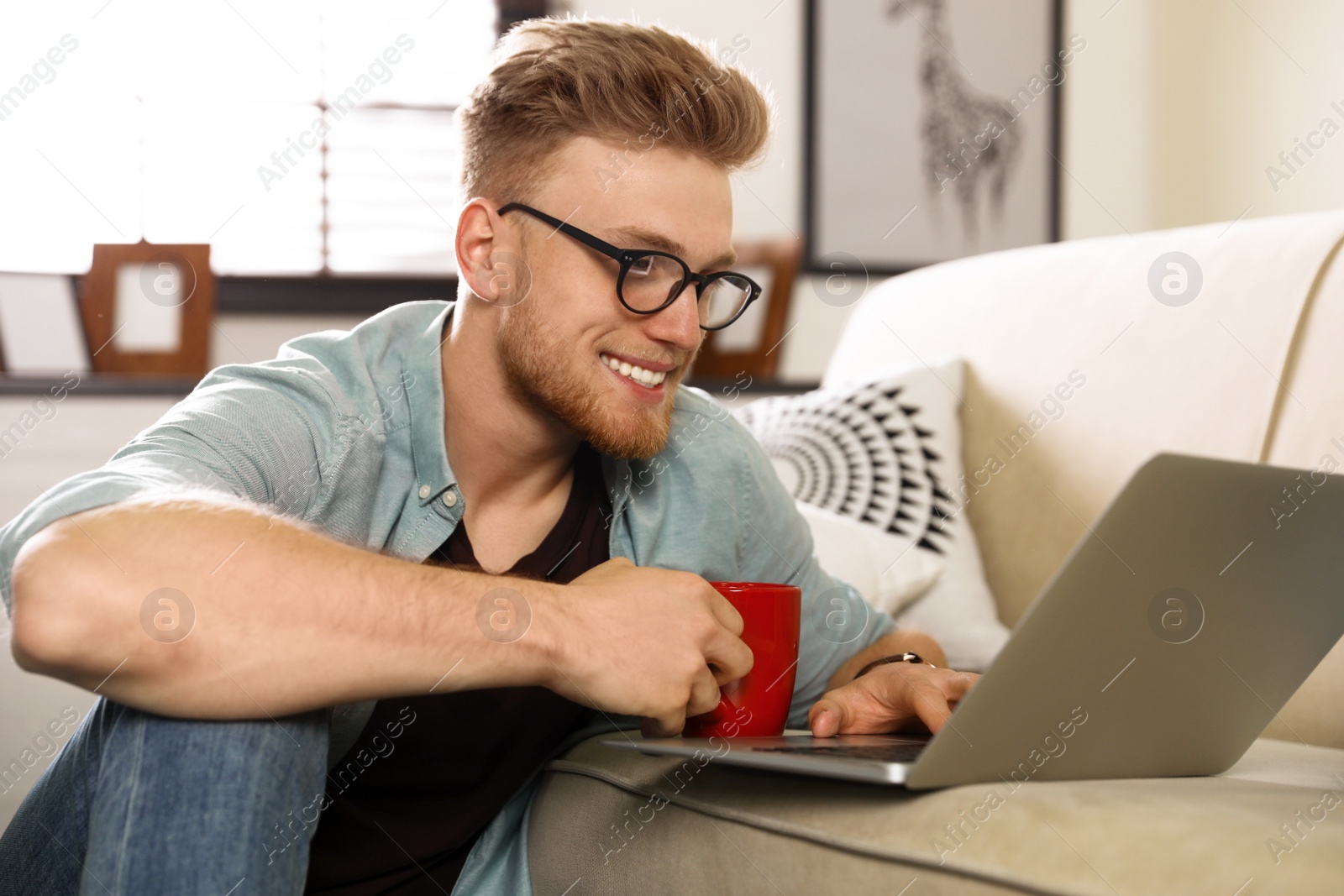 Photo of Young man using laptop in living room