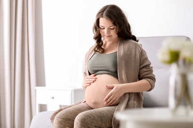 Photo of Young pregnant woman in casual clothes at home