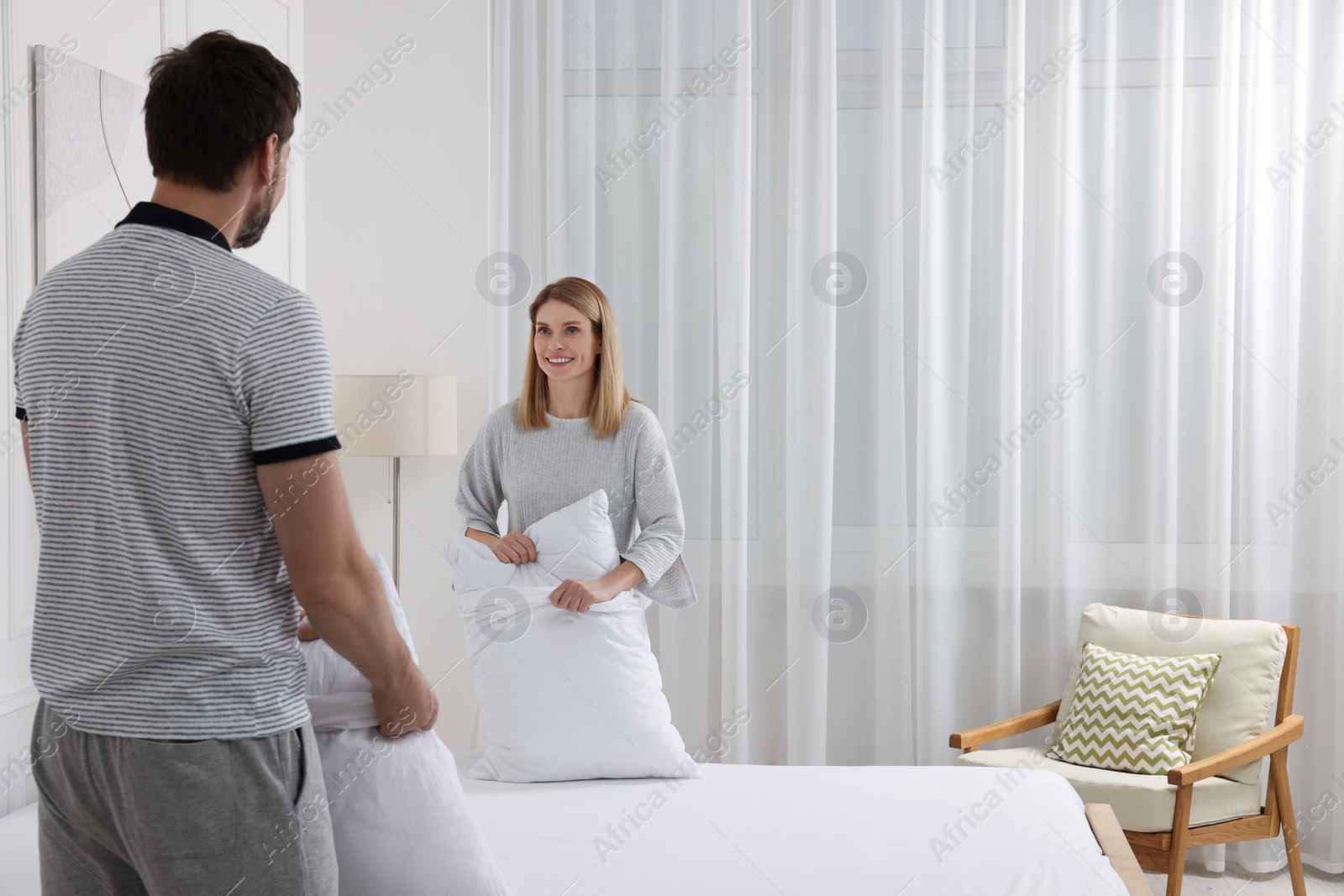 Photo of Couple changing bed linens in room. Space for text