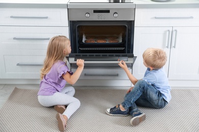 Little kids baking cookies in oven at home